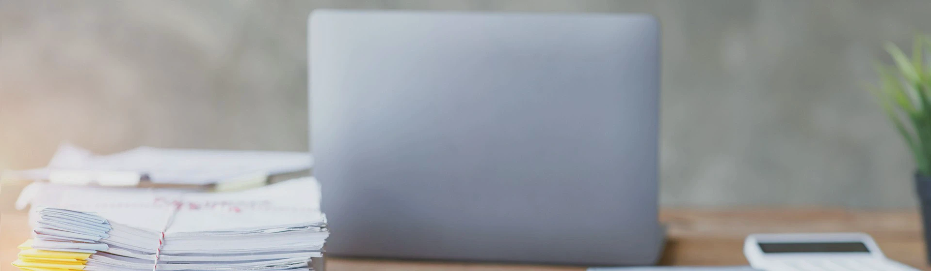 Na biurku leży szary laptop i dokumenty